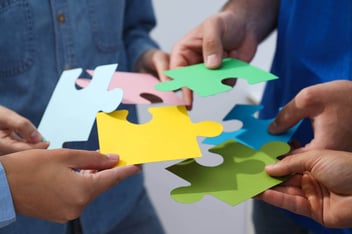 teens standing together putting puzzle together